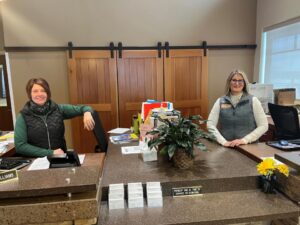 Two people sitting at a desk at the entrance to the ERL smiling at the camera