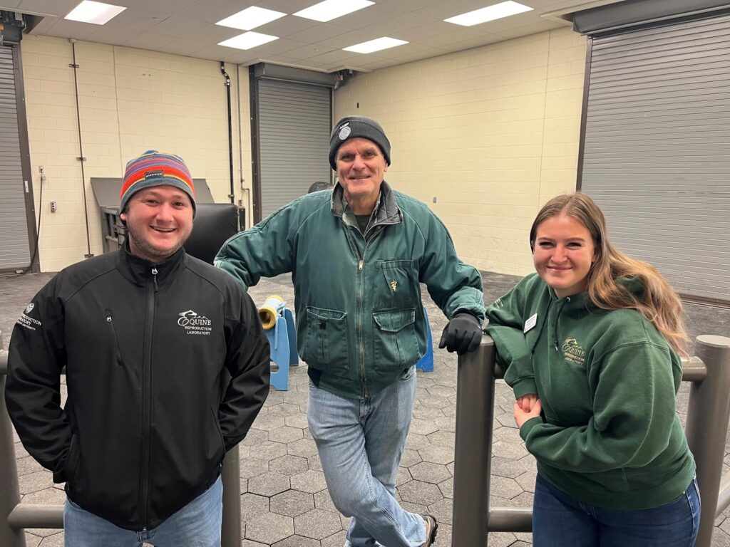 Three people in jackets and hoodies smile at the camera from inside the ERL 