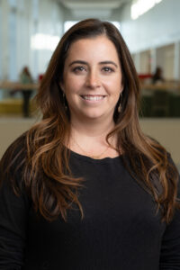 woman with brown hair wearing a black shirt smiling