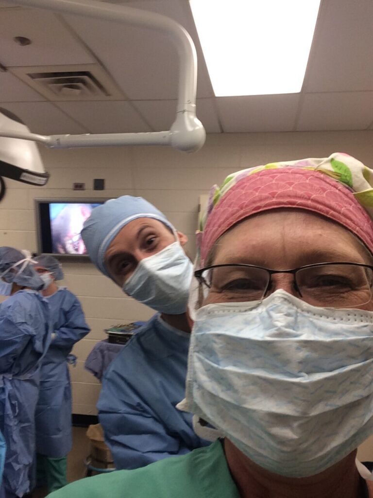 veterinary professionals in scrubs and surgical masks take a selfie in the operating room
