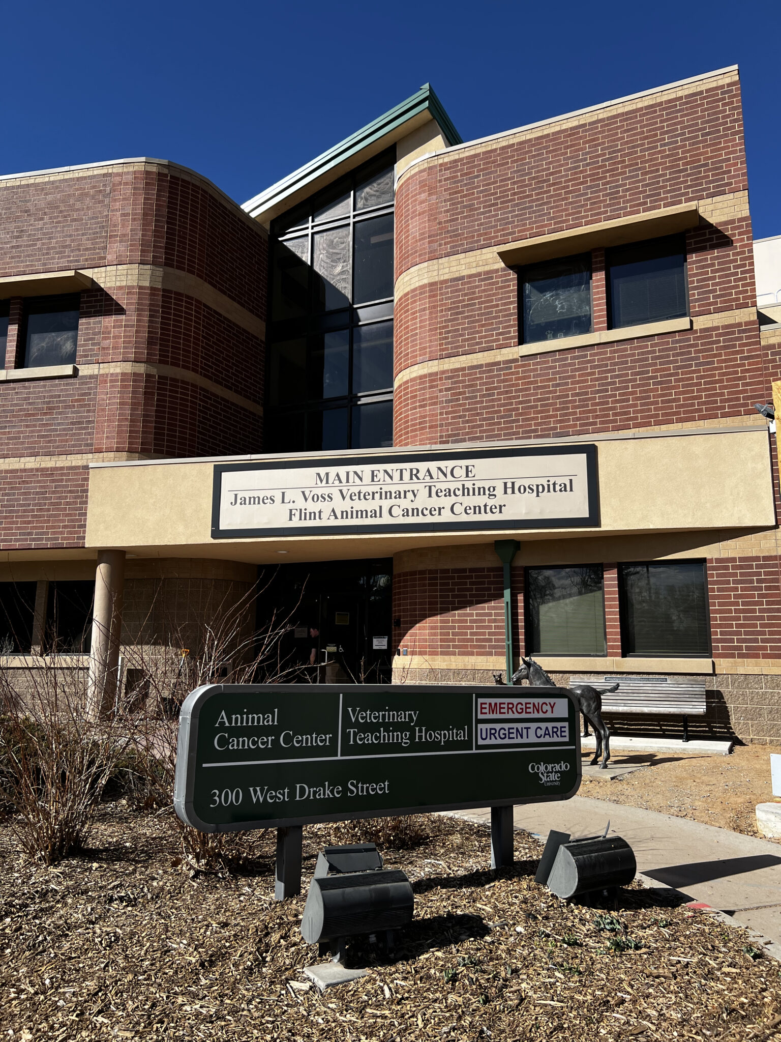 The brick entrance of the James L. Voss Veterinary Teaching Hospital with exterior signage and a green campus directory in front.