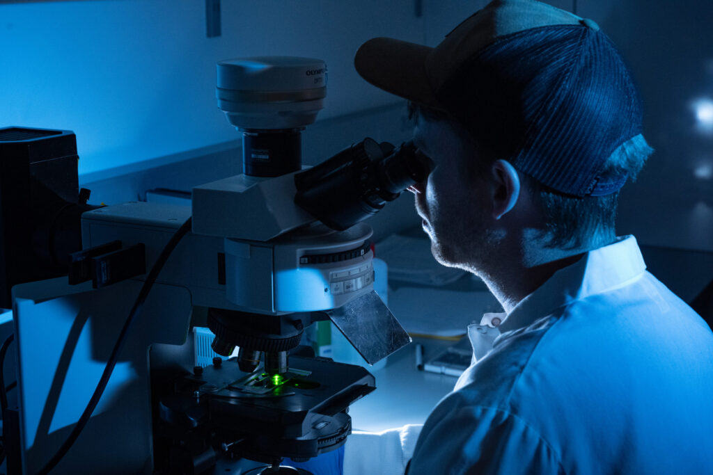 Virology lab looking into microscope in the dark