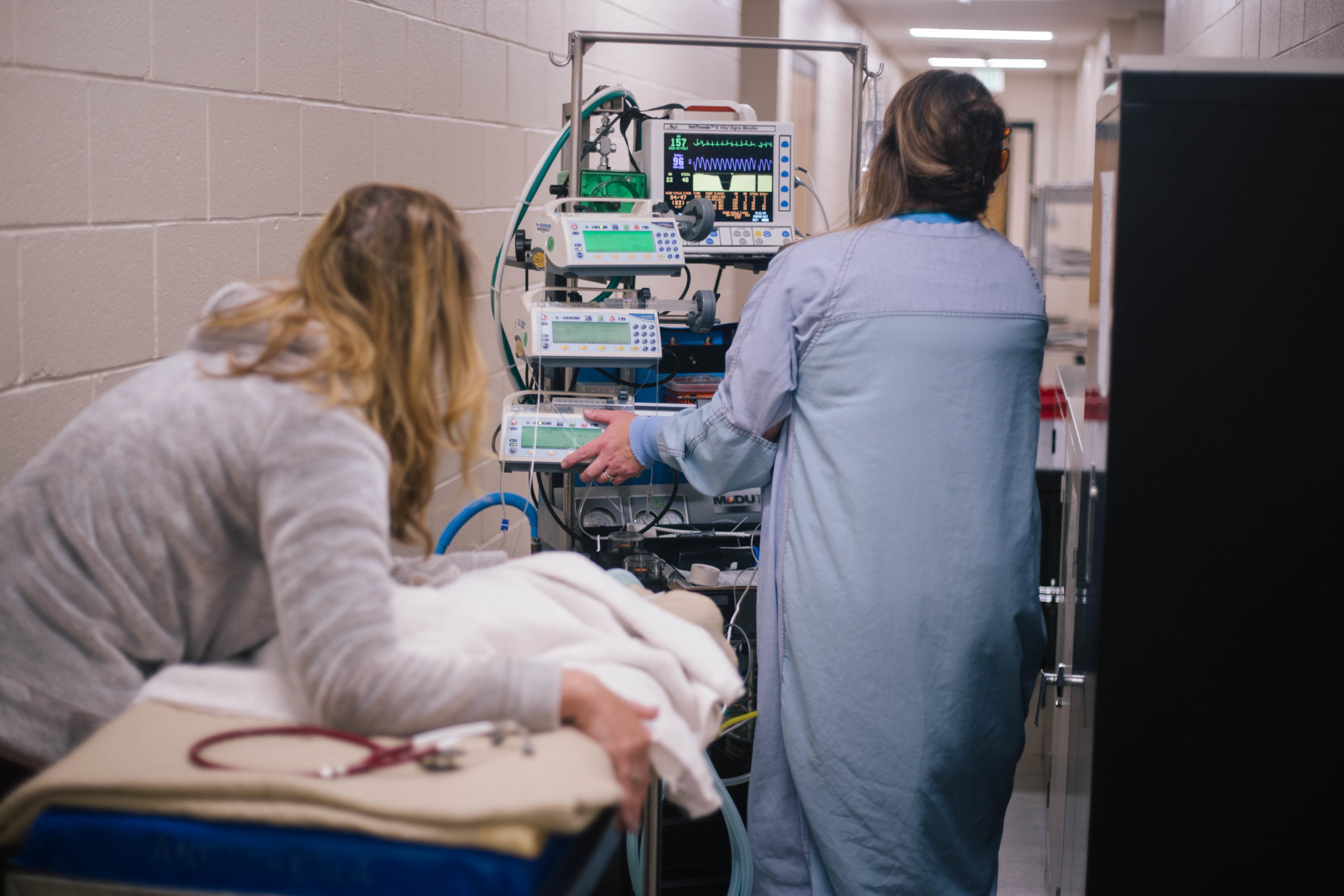 woman pushing anesthesia monitors on cart