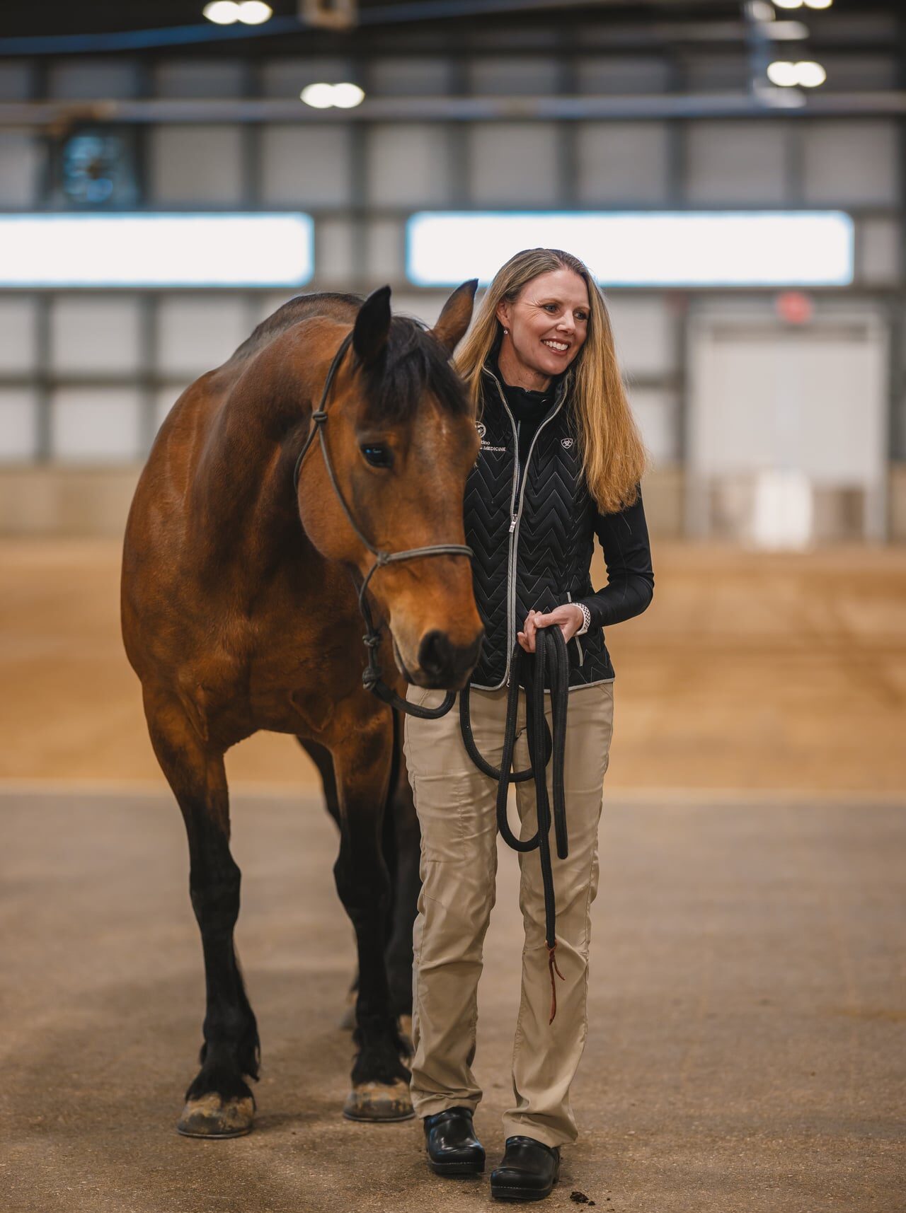 woman standing with a brown horse