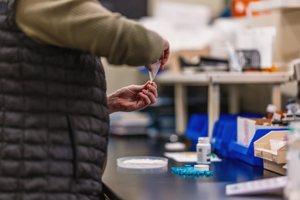 hand refilling a prescription at a veterinary pharmacy counter