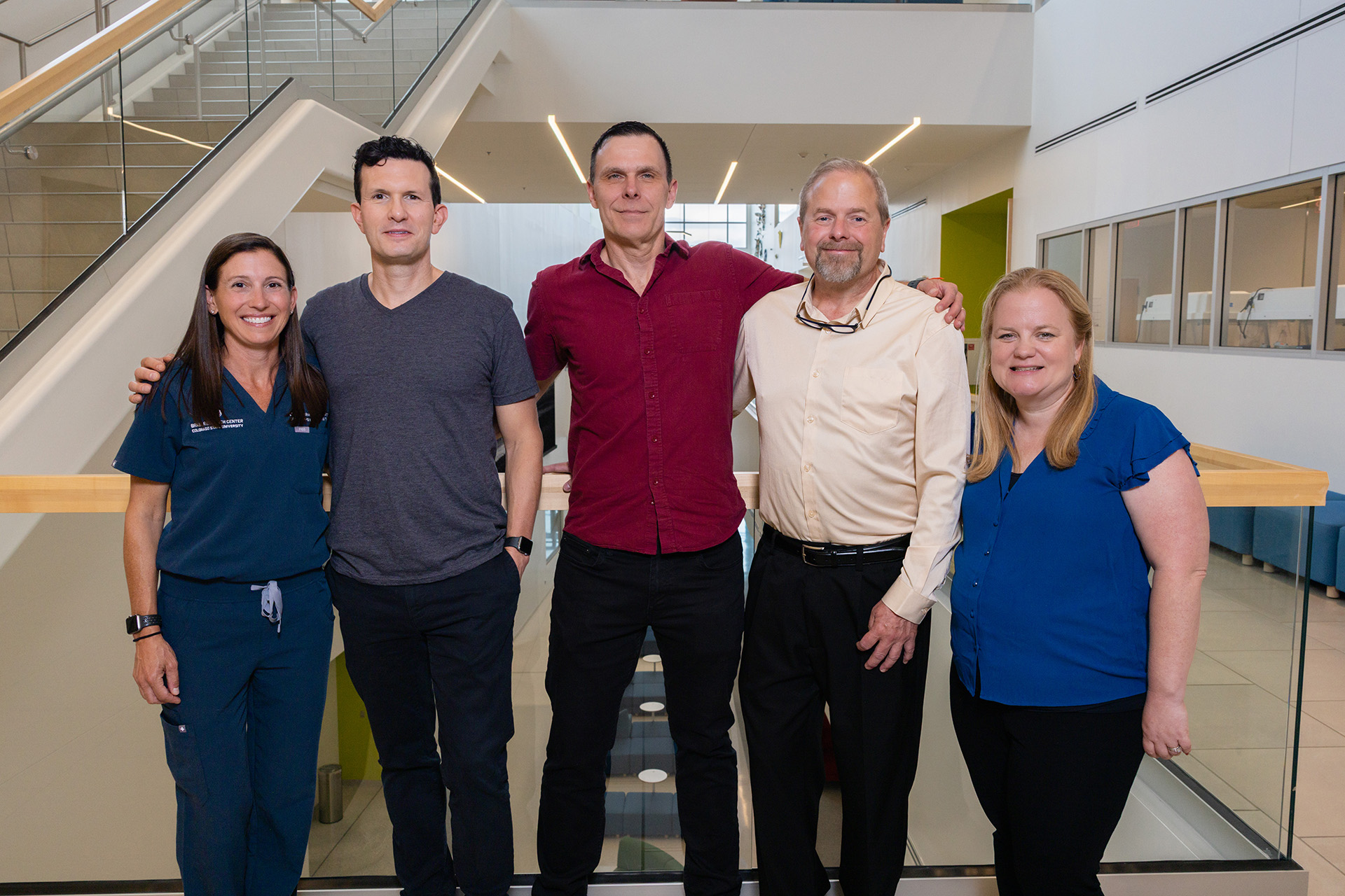 five people stand in a hallway and smile for the camera