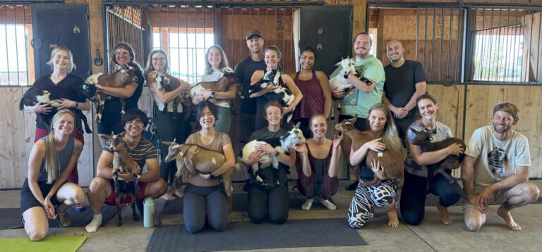 a bunch of people posing while holding baby goats