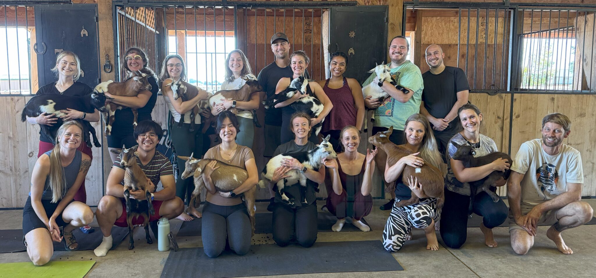 a bunch of people posing while holding baby goats