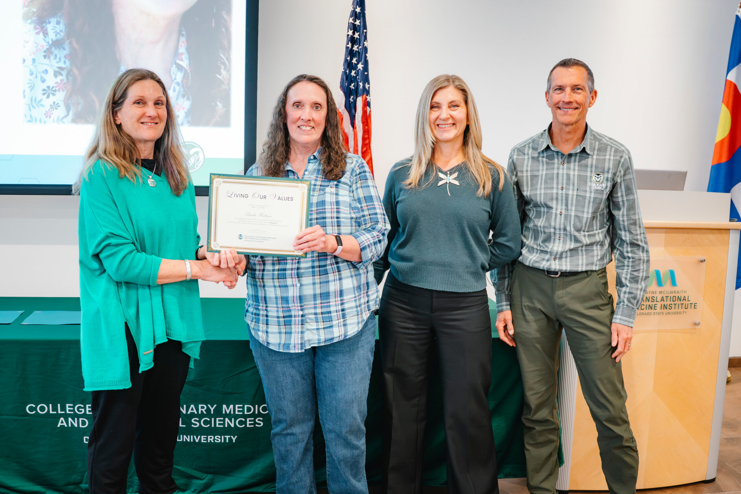 Linda Hutson poses with her award certificate surrounded by three other faculty and staff members